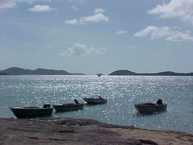 Dinghies are anchored near a rocky shore.